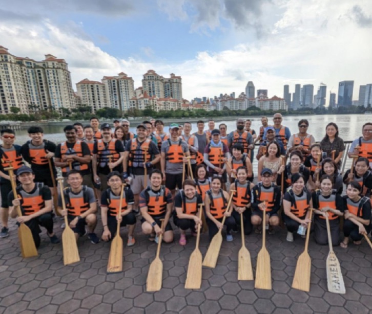 Gruppo di dipendenti con giubbotti di salvataggio che tengono in mano delle pagaie davanti a un lago